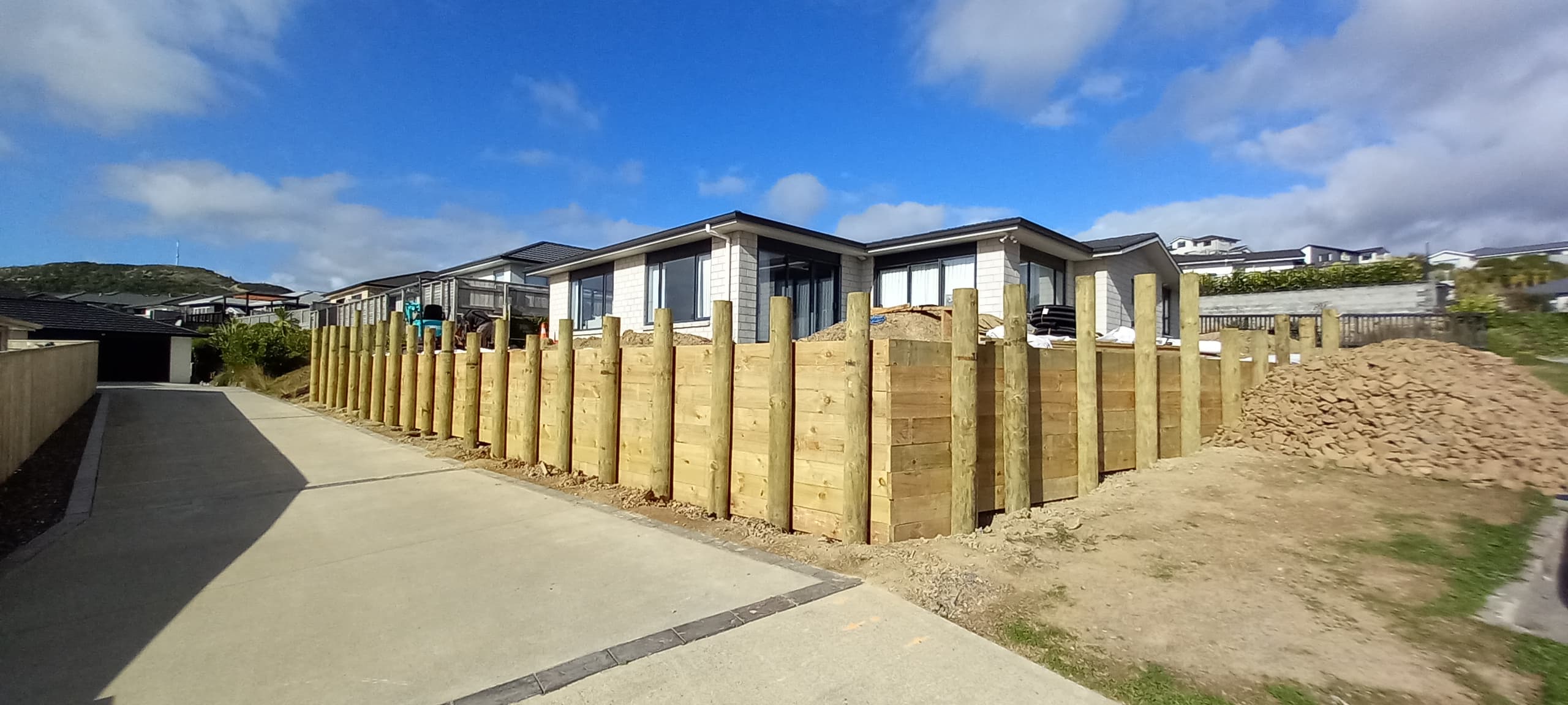 Completed timber pole and sleeper retaining wall along a footpath in Wellington